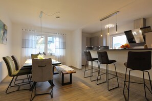 A modern kitchen with a dining area, wooden flooring, and bar stools. - Modern Apartment "Zweiradparadies" with Wi-Fi, Terrace & Garden (Mastershausen)