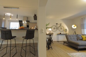 A modern kitchen with a dining area, a sofa, and a bicycle. - Modern Apartment "Zweiradparadies" with Wi-Fi, Terrace & Garden (Mastershausen)