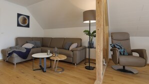 A modern living room with a sofa, a round coffee table, a floor lamp, and a chair. - Däschinger Holiday Apartment -Goldener Mond- in Mastershausen – Hunsrück Getaway for 6 Guests (Mastershausen)