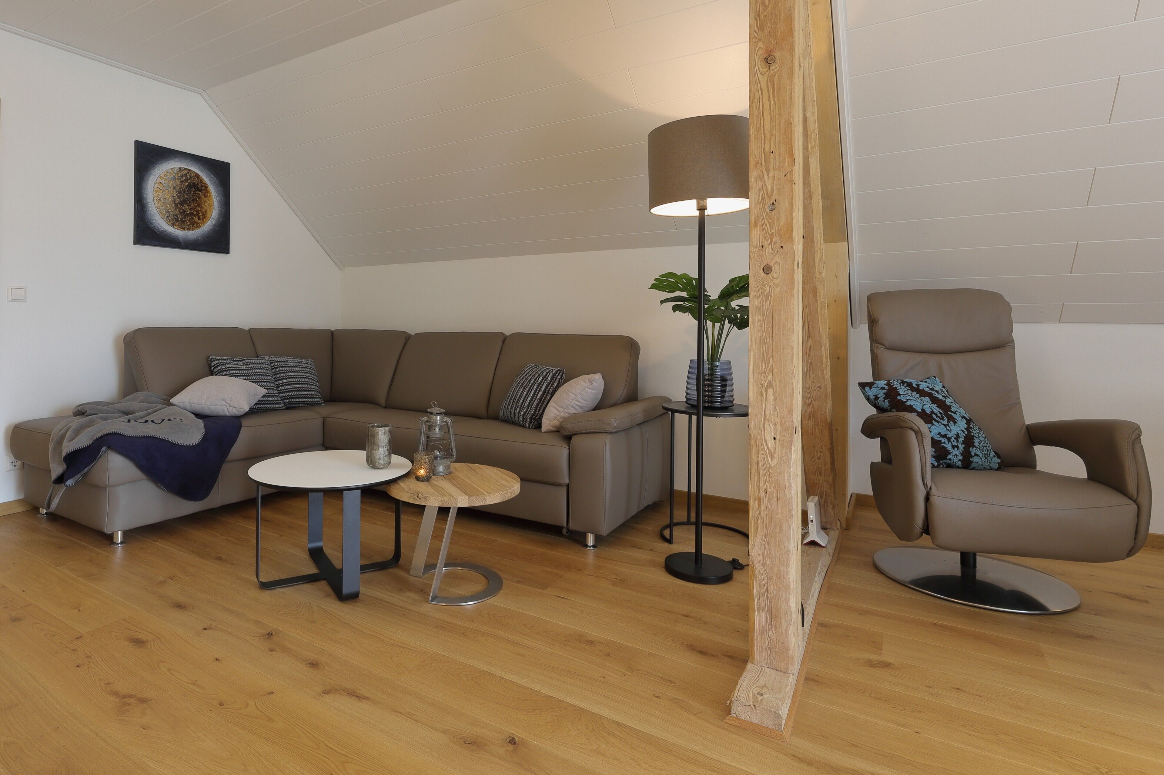 A modern living room with a sofa, a round coffee table, a floor lamp, and a chair.