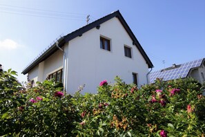 Une maison avec un toit en pente, une petite fenêtre et un panneau solaire sur le toit.