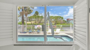 A room with a view of a swimming pool, white walls, and a window with blinds. - Boutique Hotel 2 double beds with POOL, LOCATION! 1 block to BEACH/Restaurants (Deerfield Beach)