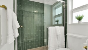 A modern bathroom with a glass shower enclosure, white fixtures, and a potted plant by the window. - Boutique Hotel 2 double beds with POOL, LOCATION! 1 block to BEACH/Restaurants (Deerfield Beach)