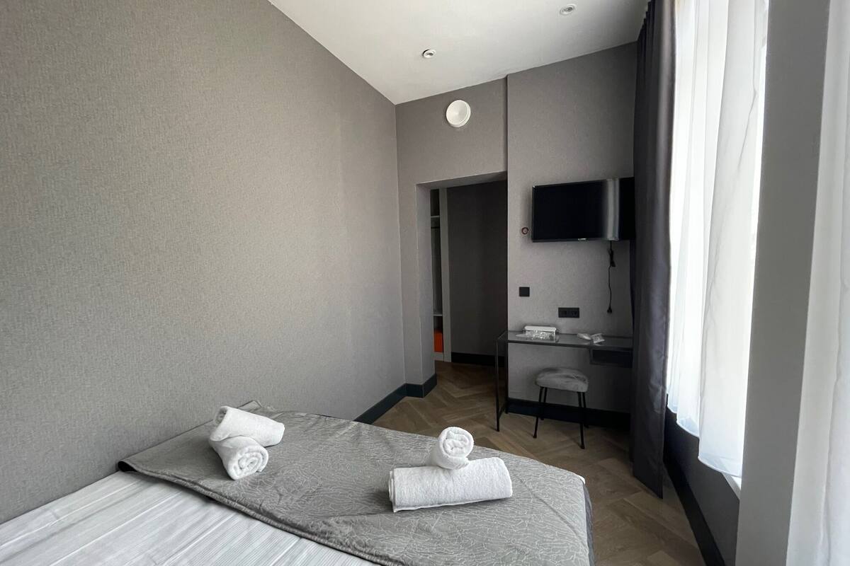 A modern hotel room with a large bed, a desk, and a TV.