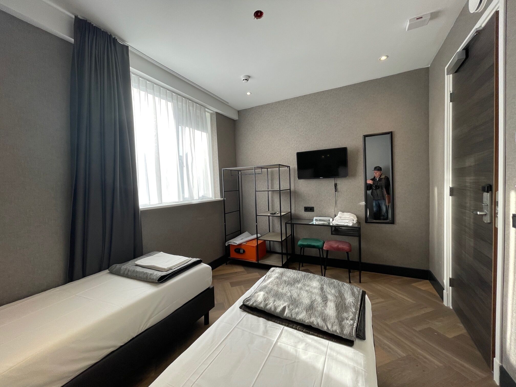 Une chambre d’hôtel avec deux lits, un bureau, une télévision et une armoire.