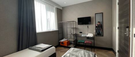 Une chambre d’hôtel avec deux lits, un bureau, une télévision et une armoire.