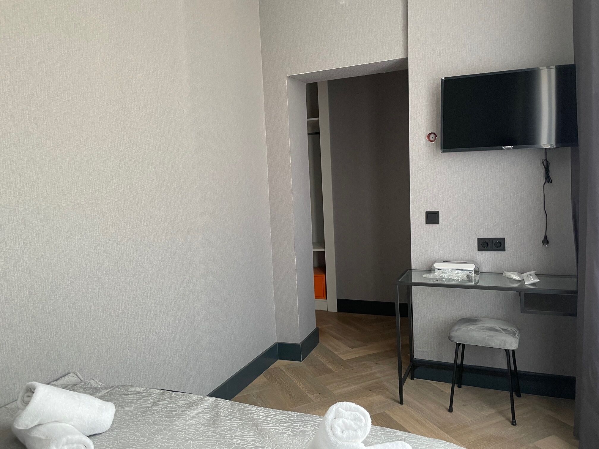 Una camera d'albergo moderna con un letto, una scrivania, una sedia, una televisione e un armadio.