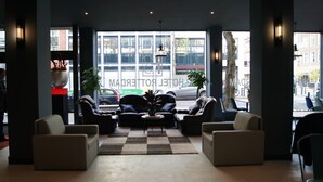 A hotel lobby with leather sofas, a checkered rug, and large windows offering a view of the street. - H3 Hotel Rotterdam City Center (Rotterdam)