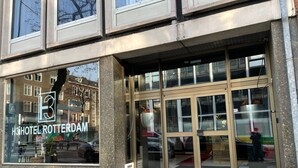 A hotel entrance with a large glass facade, a visible logo, and a tiled exterior. - H3 Hotel Rotterdam City Center (Rotterdam)