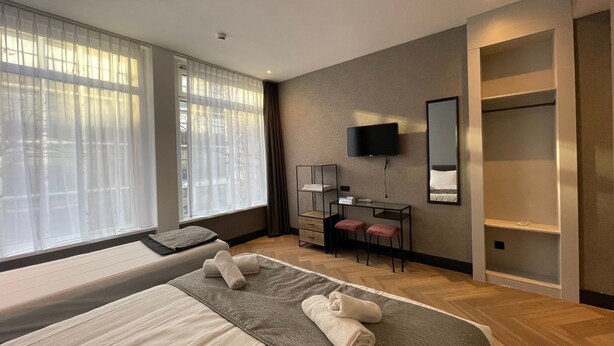 A modern hotel room with a large bed, a desk with a chair, a television, and a wardrobe. - H3 Hotel Rotterdam City Center (Rotterdam)