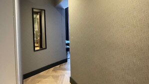 A hallway with a mirror on the left, a door at the end, and a window on the right. - H3 Hotel Rotterdam City Center (Rotterdam)