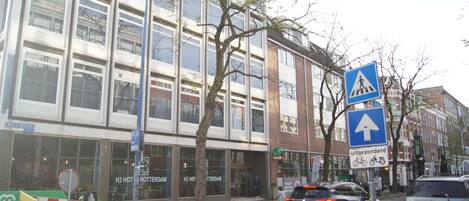 A modern building with large windows and a pedestrian crossing sign.