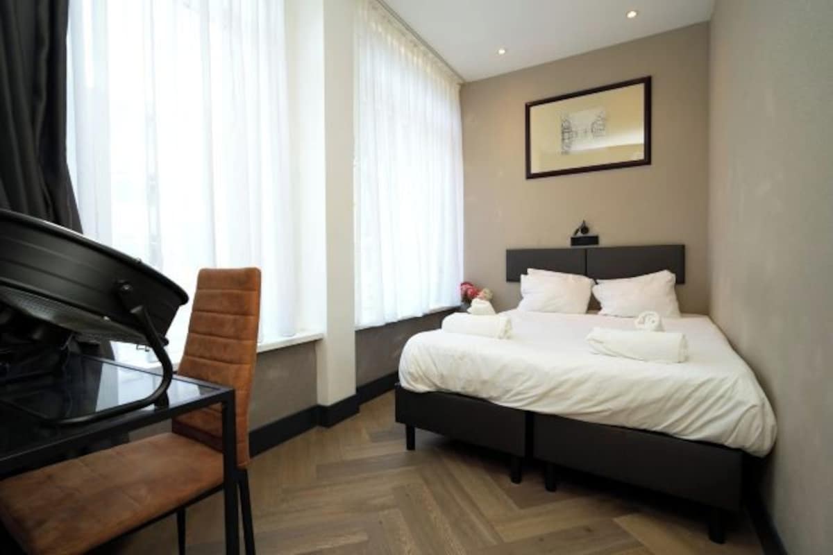 A hotel room with a bed, a desk, and a chair.