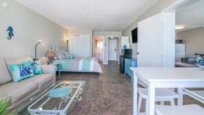 Ein kleiner Wohnraum mit Bett, Sofa, Esstisch und Küchenzeile.