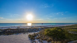 Ein Strand mit einer Holzpromenade, sandigen Dünen und einem klaren Himmel.