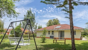 A residential property with a swing set, a small tree, and a bench in a grassy yard. - Cozy and Warm 3-bed Bungalow in Athi River (Athi River)