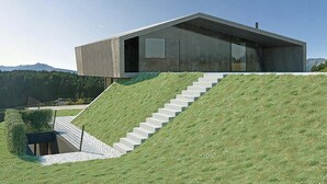Una casa moderna con una escalera empinada que conduce a un techo plano, rodeada por una colina cubierta de césped.