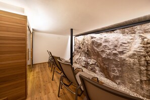 A room with a wooden floor, a stone wall, and a wooden cabinet.
