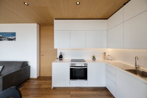 Een moderne keuken met witte kastjes, een inbouwoven en een roestvrijstalen spoelbak.