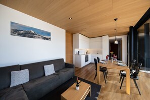 A modern living area with a sofa, a dining table, and a kitchen in the background.