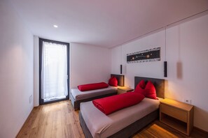Ein modernes Schlafzimmer mit zwei Betten, einem großen Fenster und einem Wandbild.
