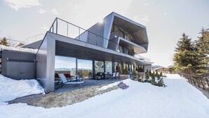 Ein modernes mehrgeschossiges Gebäude mit Balkon, großen Fenstern und verschneiter Landschaft.