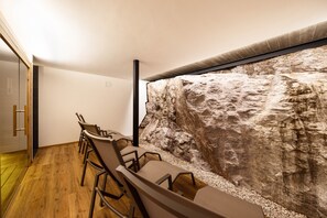 A conference room with a long table and chairs, a stone wall, and a wooden floor.