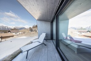 A balcony with a view of snow-capped mountains, a modern architectural style, and a glass partition.