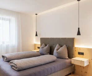 Un dormitorio moderno con una cama, dos mesitas de noche y una mesita auxiliar.