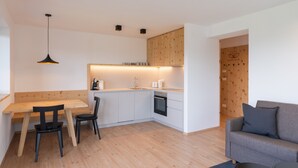 Une cuisine moderne avec un coin repas, un four encastré et un meuble en bois.