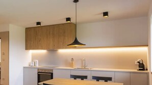 Una cocina moderna con una mesa de madera, sillas negras e iluminación colgante.