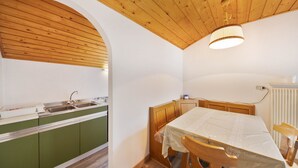 A kitchen with wooden cabinets, a sink, and a table with chairs. - Holiday Apartment "Grödnerhof - Almöhi" Mountain View, Wi-Fi, Garden & Balcony (Breien / Tiers)