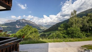 A mountain view from a wooden building with a paved road in the foreground.