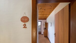 A hallway with a wooden door, a wooden ceiling, and a wall-mounted sign with the number '2'.