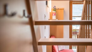 A room with a bed, a wooden chair, a window with a view, and a small table with a vase. - Apartment "Kreuzhof rechts" with Mountain View, Wi-Fi, Balcony & Garden (Neustift)
