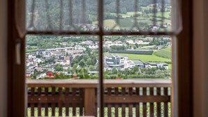 A view through a window with a wooden frame, displaying a town with buildings and greenery. - Apartment "Kreuzhof links" with Mountain View, Wi-Fi, Balcony & Garden (Neustift)