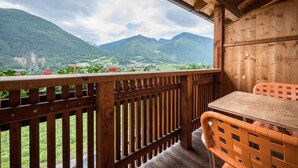 A wooden balcony with a table and chairs, overlooking a mountainous landscape. - Apartment "Kreuzhof links" with Mountain View, Wi-Fi, Balcony & Garden (Neustift)