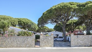 Eine steine Mauer mit einem Tor, ein geparktes Auto und ein Haus mit rotem Dach.