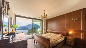 Ein Schlafzimmer mit einem großen Bett, einem Holzschrank, einem Schminktisch, einem Nachttisch und einer Kronleuchter.