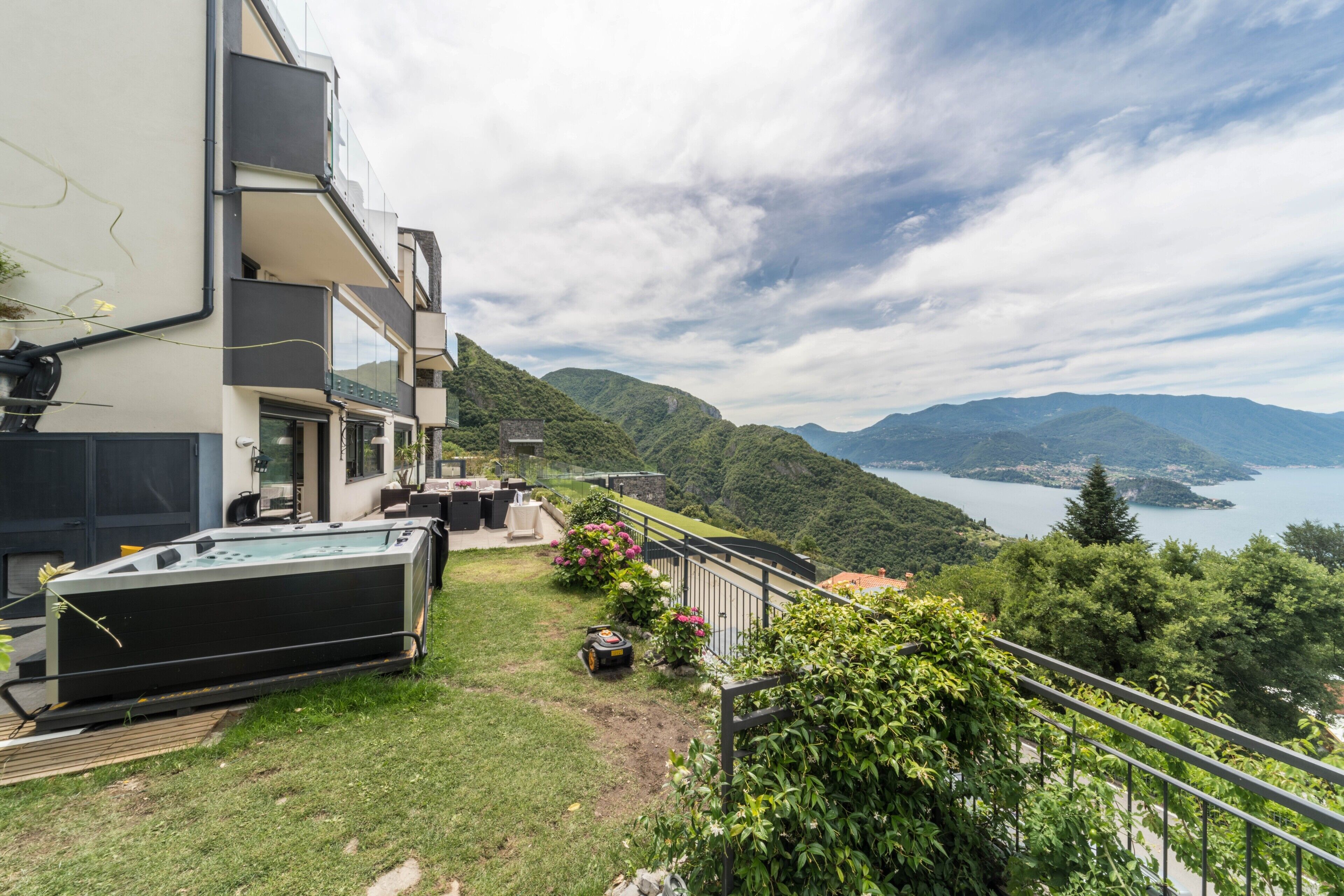 Un bâtiment moderne doté d’une piscine, d’un espace extérieur aménagé et offrant une vue panoramique sur les montagnes et un lac.