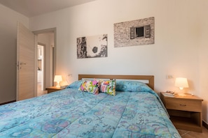 Una camera da letto con un letto, due comodini con lampade, una porta in legno e due quadri appesi al muro.