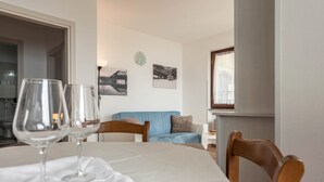 Ein Esstisch mit zwei Weingläsern, ein blaues Sofa und eine Wanduhr.