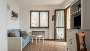 Ein Wohnzimmer mit einer Couch, einem kleinen Tisch, einem Fernseher und einem Schrank.