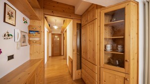 Ein Holzinnenraum mit einem Flur, der zu einem Küchenbereich führt, inklusive Schränken und einem Kühlschrank.