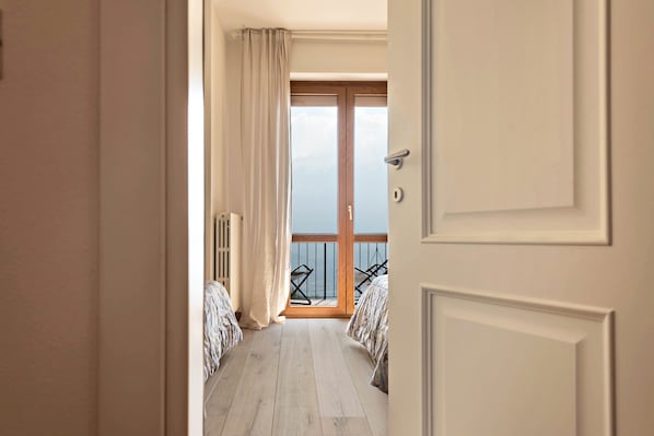 A hotel room with a balcony, a wooden floor, and a view of the sky.