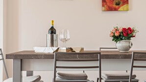 A dining table with a bottle, wine glasses, and a vase of flowers.