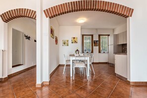 A spacious kitchen with white cabinets, a dining area with a table and chairs, and a tiled floor.