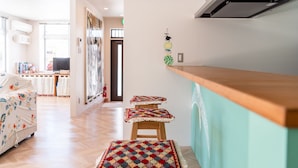 Una cucina moderna con un piano di lavoro in legno, una panca con un cuscino colorato e vista sull'area living.