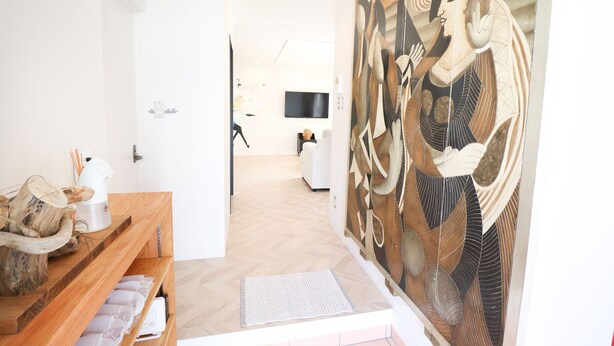 Una camera d'albergo moderna con una scrivania di accoglienza in legno, un'ampia opera d'arte astratta, una televisione a schermo piatto e un design minimalista.