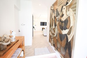 Ein modernes Hotelzimmer mit einem Holzerreptionsschalter, einem großen abstrakten Gemälde, einem Flachbildfernseher und einem minimalistischen Design.